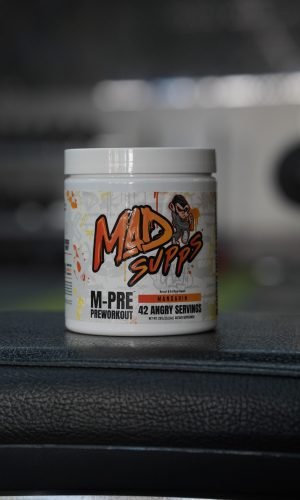 White container of Mad Supps M-Pre Preworkout powder with orange/black logo, Mandarin flavor, 42 servings, on a dark surface.